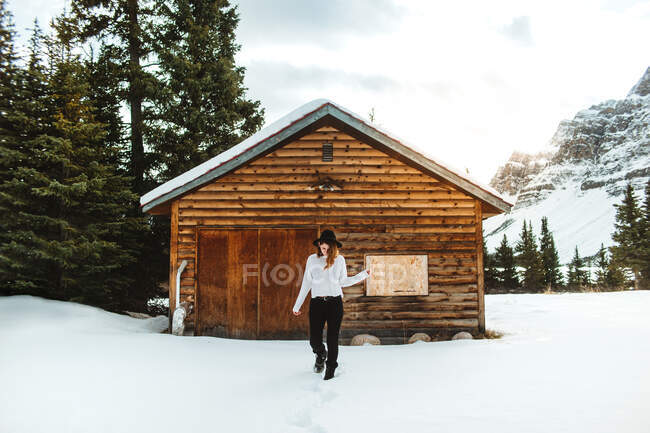 Trendy female walking on show near lumber hut on shore of Bow Lake on winter day in Alberta, Canada — Stock Photo