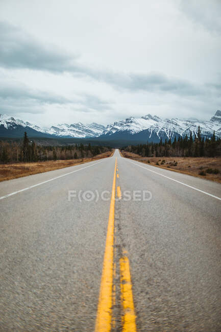 David Thompson Highway contra montanhas nevadas em dia nublado no Parque Nacional de Banff — Fotografia de Stock