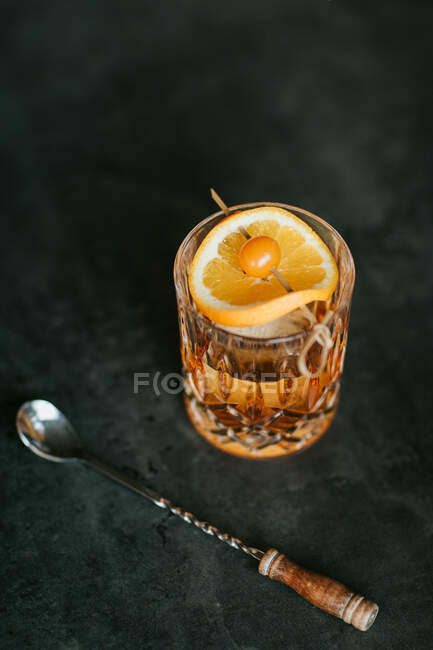 Composizione di whisky freddo ghiacciato guarnito con fetta di limone e posto sul tavolo nero — Foto stock