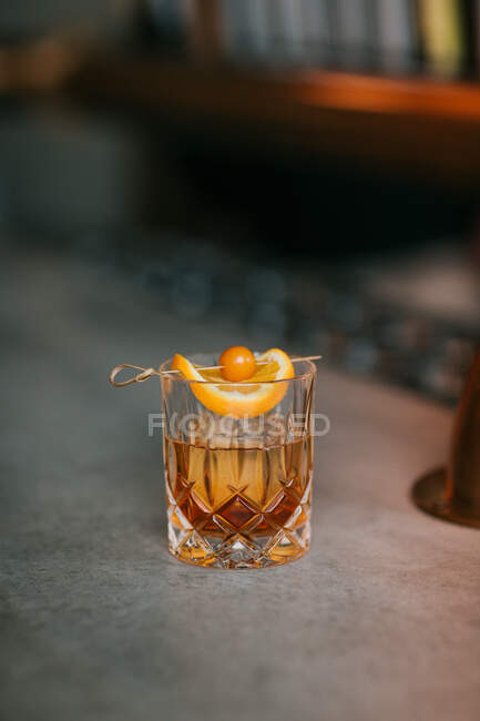 Composition of cold icy whiskey garnished with lemon slice and placed on concrete table — Stock Photo