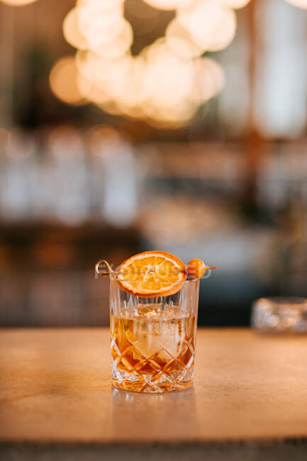 Zusammensetzung von kaltem, eisigem Whisky, garniert mit Zitronenscheibe und nachts in einer Bar auf einem Betontisch platziert — Stockfoto