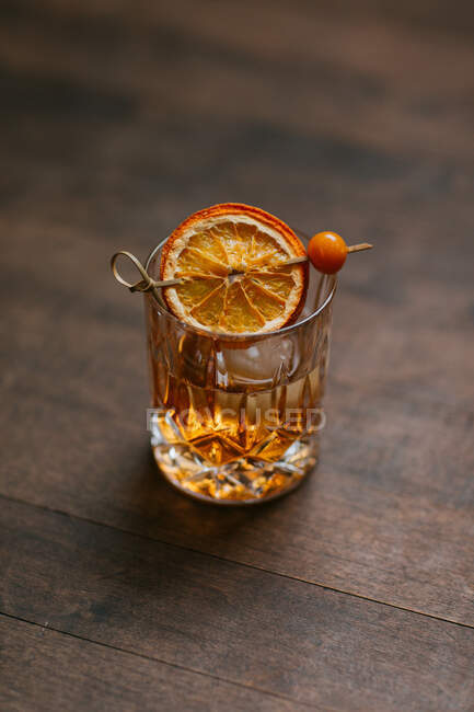 De composición superior de whisky helado frío adornado con rodaja de limón y colocado en la mesa de madera - foto de stock