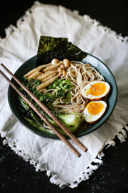 From above of ceramic bowl with delicious ramen and chopsticks placed on table covered with white tablecloth — Stock Photo