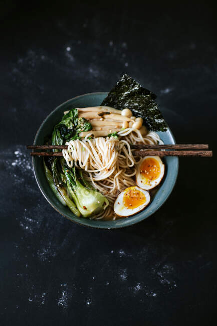 Top view of ceramic bowl with delicious ramen and chopsticks placed on table — Stock Photo