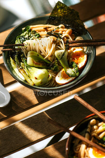 From above bowl with tasty ramen for lunch placed on wooden table in cafeteria — Stock Photo