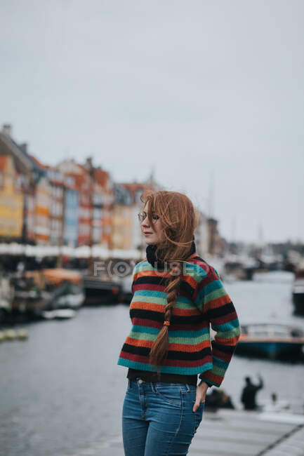 Mujer de pie con los ojos cerrados contra barcos amarrados en la orilla del canal en Copenhague - foto de stock