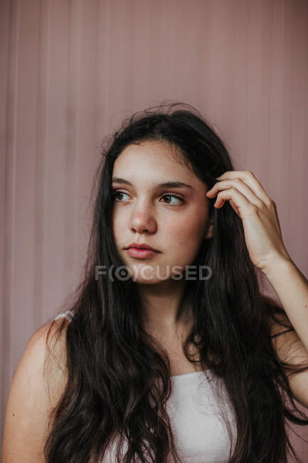 Calm dreamy female teenager with long dark hair standing looking away against plank wall — Stock Photo