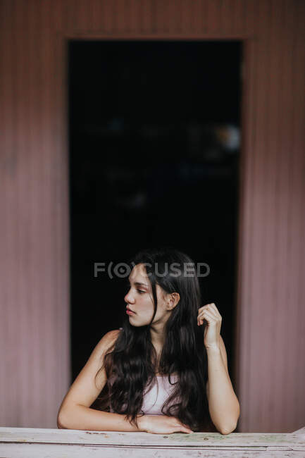 Adolescente rêveuse calme avec de longs cheveux foncés regardant loin contre le mur de planche — Photo de stock