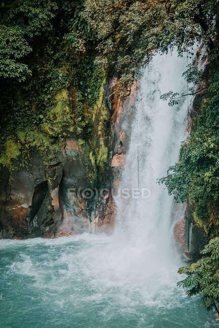 Paesaggio pittoresco di cascata che cade da ripida roccia circondata da una lussureggiante vegetazione tropicale nella provincia di Alajuela in Costa Rica — Foto stock