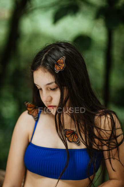 Tranquil young female in bikini with ornamental butterflies on body and hair standing against blurred green foliage during summer adventure in Costa Rica — Stock Photo