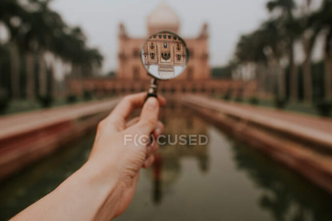Crop anonymous traveler showing upside down reflection of old stone Safdarjungs Tomb located in New Delhi — Stock Photo