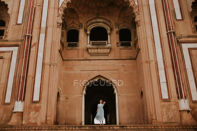 From below full body of female traveler standing against archway of Safdarjungs Tomb historic landmark of New Delhi — Stock Photo