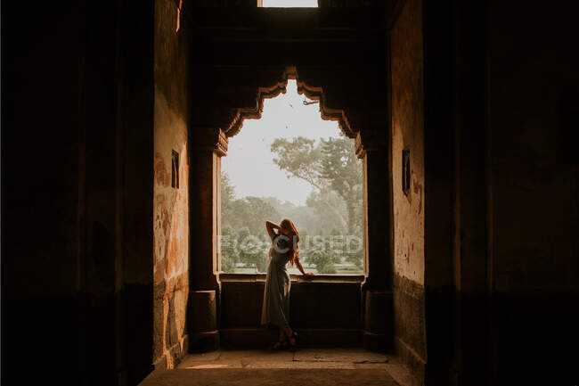 Vista trasera de cuerpo completo del viajero femenino irreconocible con la mano en la cabeza en el edificio histórico envejecido en Lodi Garden en Nueva Delhi - foto de stock