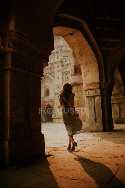 Corpo inteiro de volta vista de turista feminino anônimo correndo sob passagem arqueada de Muhammad Shah Sayyid túmulo em Lodhi Garden em Nova Deli — Fotografia de Stock