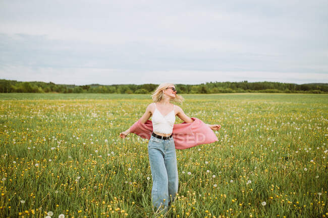 Счастливая молодая женщина стоит на лугу летом — стоковое фото