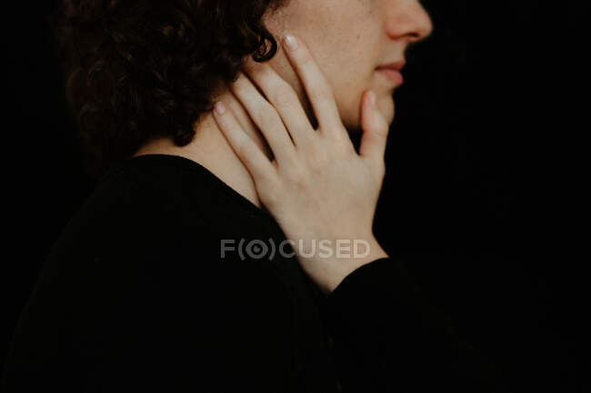 Vista laterale della ragazza delle colture delicatamente toccando il viso del fidanzato irriconoscibile su sfondo nero in studio — Foto stock
