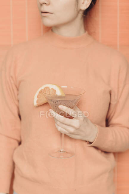 Crop unrecognizable female with glass of refreshing pink martini cocktail with chia seeds and grapefruit slice — Stock Photo