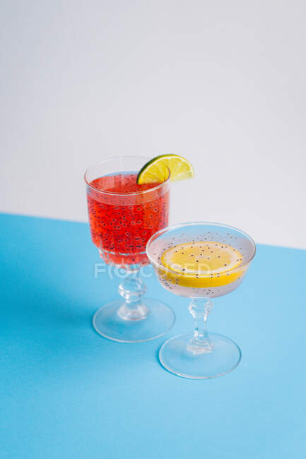 Dall'alto di bicchieri con rinfrescanti cocktail freddi con fette di agrumi e semi di chia serviti sul tavolo in studio — Foto stock