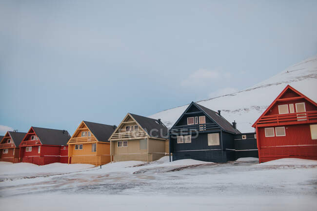 Casas de madera coloridas ubicadas en el pueblo en las tierras altas nevadas en invierno en Svalbard - foto de stock