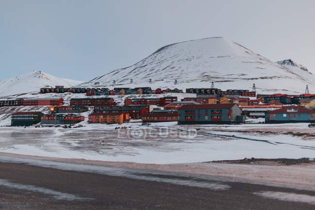 Maisons résidentielles rouges situées dans la vallée enneigée dans les hautes terres en hiver sur fond de ciel couchant à Svalbard — Photo de stock