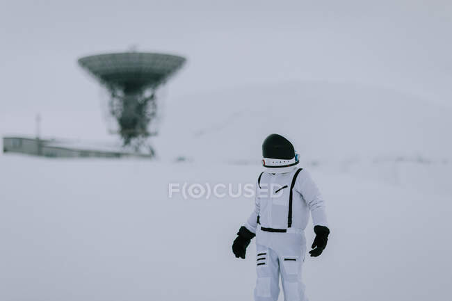 Cosmonauta irriconoscibile in tuta spaziale in piedi nella valle innevata in inverno sullo sfondo di enormi antenne radar nelle Svalbard — Foto stock