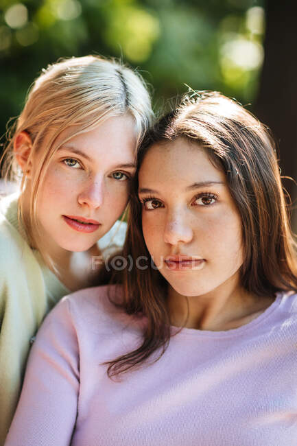 Нежные сестры-подростки смотрят в камеру в солнечный летний день в зеленом саду — стоковое фото