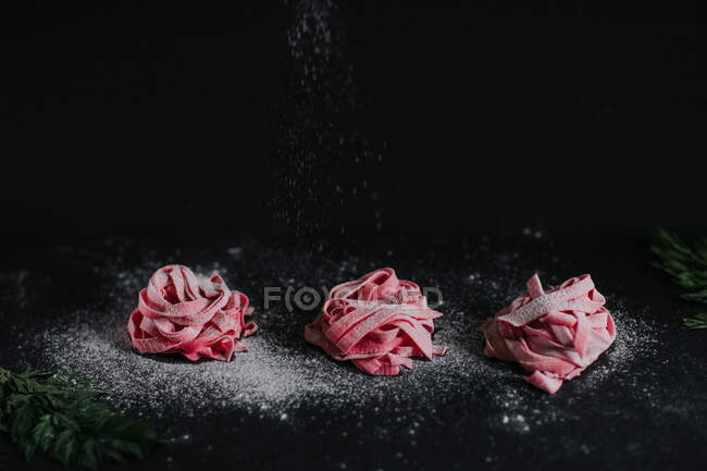 Appetizing vegan beetroot pasta of pink color served on black table in studio — Stock Photo