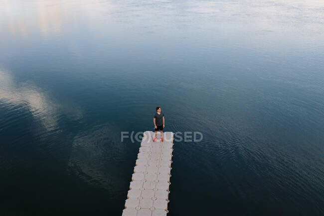 De cima visão remota do macho em pé na borda do cais perto do lago calmo — Fotografia de Stock