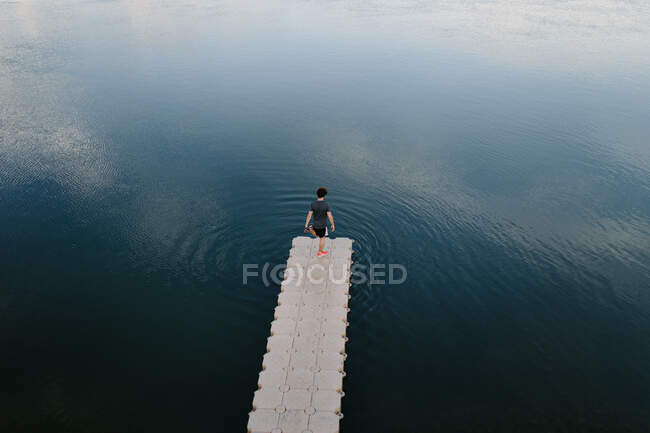 From above remote view of male standing on edge of quay near calm lake — Stock Photo