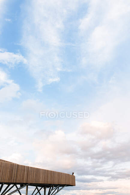 Vista remota di persona in piedi sul punto di vista in legno sullo sfondo di sorprendente cielo nuvoloso tramonto — Foto stock
