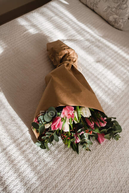 Bouquet incroyable de tulipes sur le lit dans une chambre lumineuse et ensoleillée pour les valentines — Photo de stock