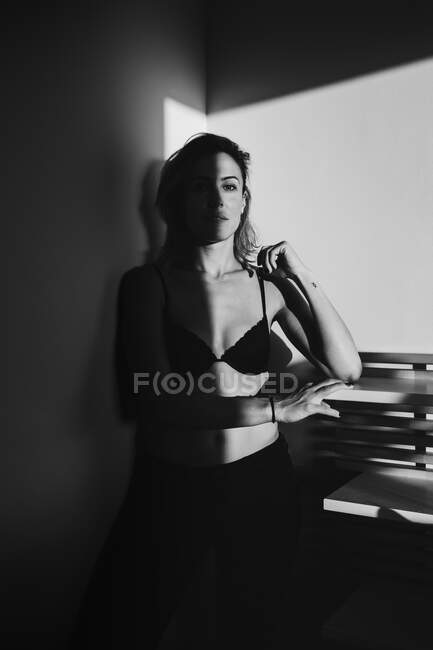 Tournage noir et blanc d'une jolie femme sensuelle jouant entre lumière et ombre en lingerie — Photo de stock
