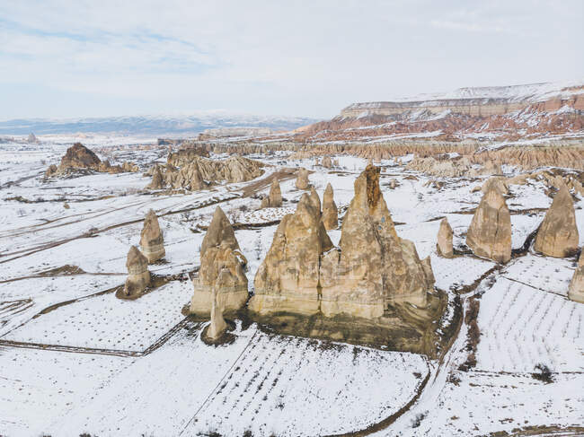 Pittoresca veduta drone di formazioni rocciose situate nella campagna innevata nella giornata invernale in Cappadocia, Turchia — Foto stock