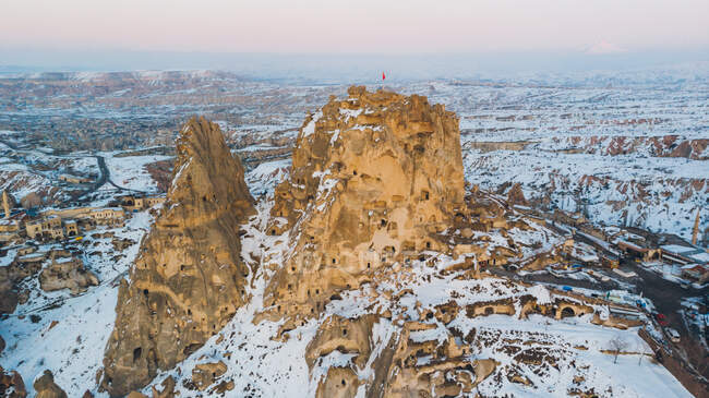 Aerial view of rough rock formations covered with white snow against cloudless evening sky in Cappadocia, Turkey — Stock Photo