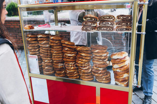 Crop femelle debout en sélectionnant des petits pains frais de vitrine près des vendeurs de cultures sur la rue de la ville en Turquie — Photo de stock