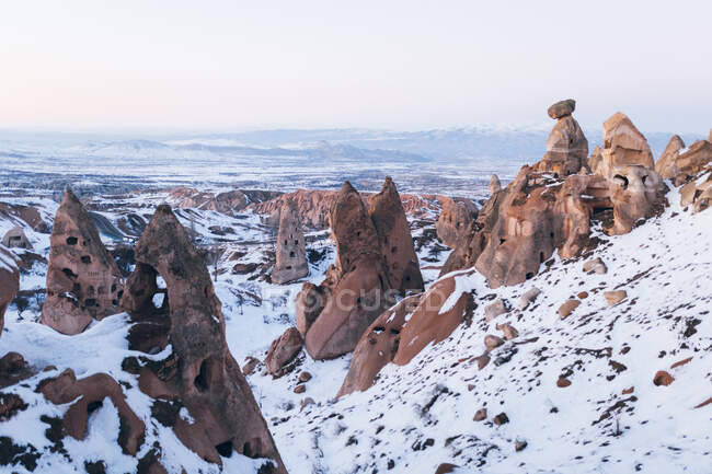 Formations rocheuses rugueuses recouvertes de neige blanche contre un ciel nocturne sans nuages en Cappadoce, Turquie — Photo de stock