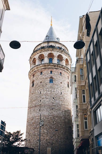 Desde abajo envejecido Torre Galata situado cerca de edificio residencial contra el cielo nublado en la calle de Estambul, Turquía - foto de stock