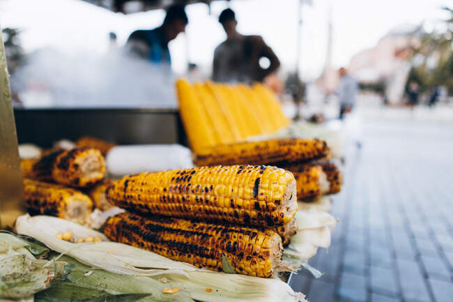 Des épis de maïs frais crus et frits disposés sur le stand du restaurant de rue contre le pot fumé en ville en Turquie — Photo de stock