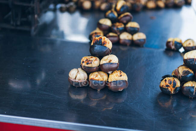 Високий кут купи смачних смажених каштанових горіхів, розміщених на металевій стійці на ринку в Туреччині. — стокове фото