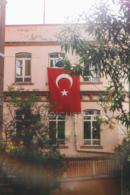 National flag hanging on wall of residential building on city street on sunny day in Turkey — Stock Photo