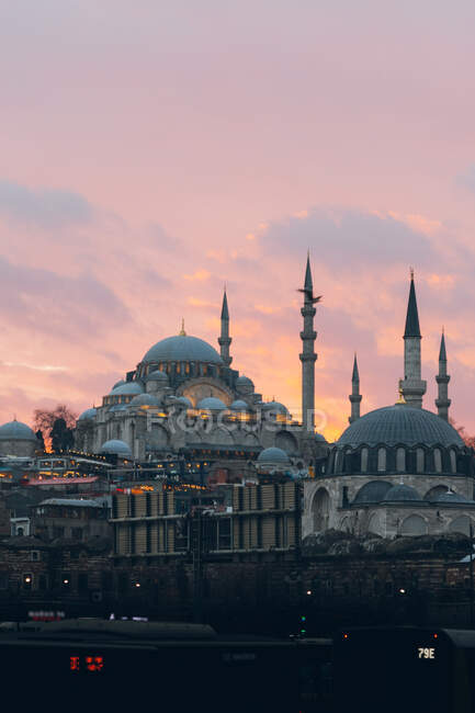 Mosquées âgées et bâtiments résidentiels situés contre un ciel nuageux et ensoleillé avec des oiseaux volants en soirée en Turquie — Photo de stock