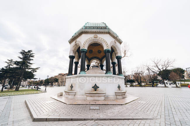 Angle bas de la vieille fontaine ornementale orientale située sur la chaussée contre le ciel nuageux dans le parc de la ville en Turquie — Photo de stock
