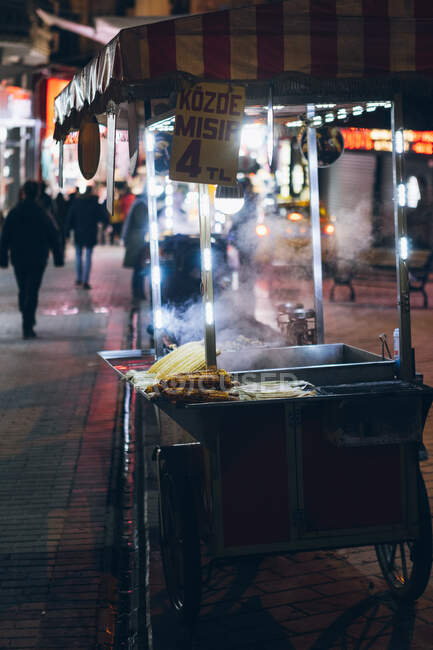 Unrecognizable cook preparing traditional dishes for selling in stall against street with people walking in illumination at night in city of Turkey — Stock Photo