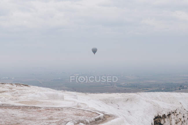 View from salt mountain of air balloon flying in gray sky over countryside in thick fog in overcast weather in Turkey — Stock Photo