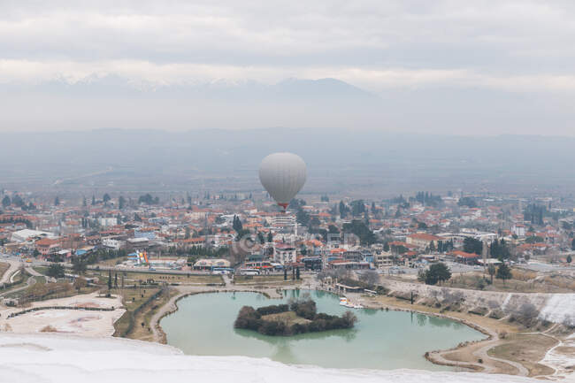 Vue aérienne du grand ballon aérien gris qui court dans un ciel nuageux au-dessus d'une ville brumeuse par temps frais et couvert en Turquie — Photo de stock