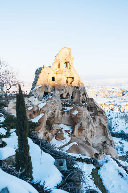 De cima do castelo envelhecido esculpido na rocha e coberto da neve branca contra céu cloudless na rua do assentamento de Uchisar em Capadócia, Turquia — Fotografia de Stock