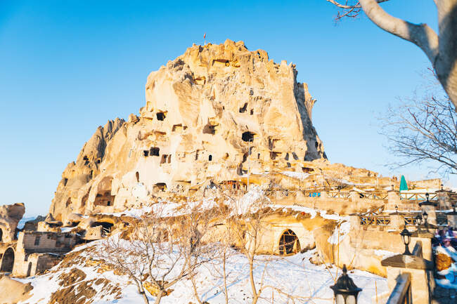 Низький кут старого замку, висічений у скелі і покритий білим снігом на безхмарному небі на вулиці Учисар поселення в Каппадокії (Туреччина). — стокове фото