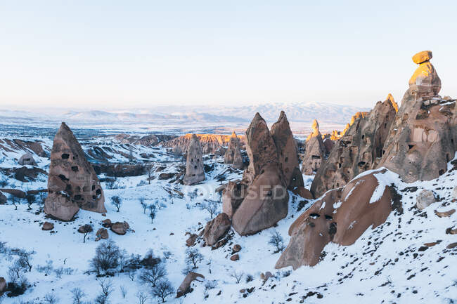 Aerial view of rough rock formations covered with white snow against cloudless evening sky in Cappadocia, Turkey — Stock Photo