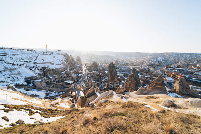 З вище відомого поселення з давніми кам'яними будівлями, які знали, що це казкові будинки в долині проти снігового пагорба в зимовий сонячний день в Туреччині. — стокове фото