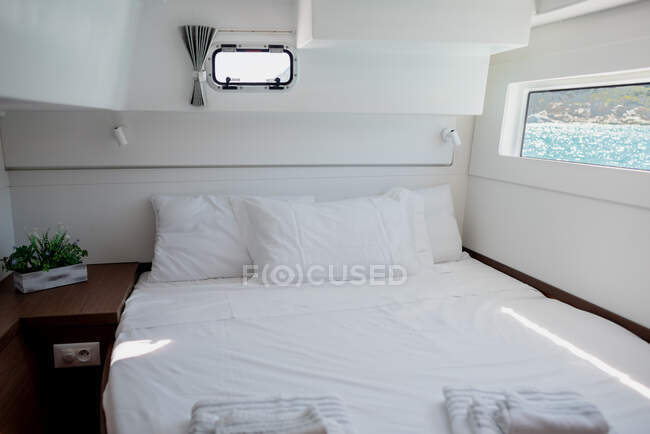 Interior of bedroom in cabin of catamaran with comfortable bed with white bedclothes — Stock Photo